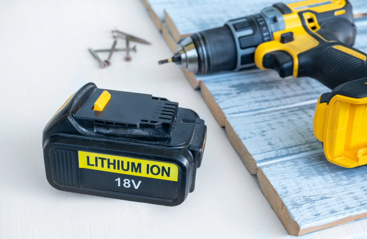 A lithium ion battery sits beside a power tool